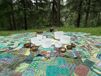 Crystal and Tibetan bowls on patchwork quilts in a clearing ringed by fir trees